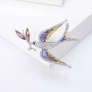 Elegant swallow brooch with colorful enamel wings and sparkling crystals on a white pedestal