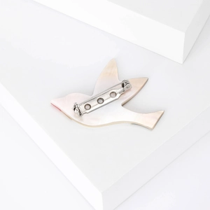 Broche toucan élégante en nacre sur un support géométrique blanc minimaliste