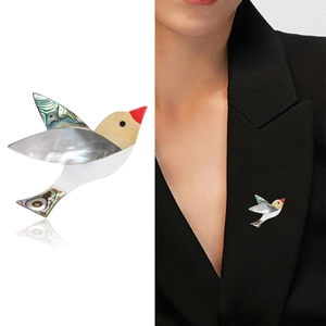Élégante broche toucan avec incrustation de nacre sur costume noir et fond blanc épuré