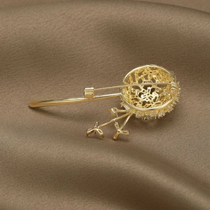 Élégante broche pissenlit dorée avec zircons brillants sur un fond de tissu en soie luxueux