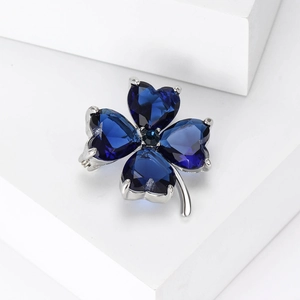 Detail of four-leaf clover brooch with blue heart-shaped crystals on silver base