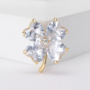 Elegant gold four-leaf clover brooch with transparent crystal heart petals on white base