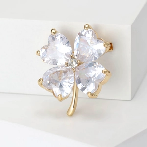 Macro shot of heart-shaped crystal petals on a gold clover brooch with detailed metal work