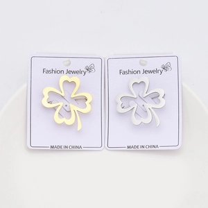 Detail of gold and silver four-leaf clover brooches on a jewelry card in a white tray