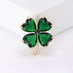 Macro detail of high-end emerald green crystal clover brooch with golden metal setting