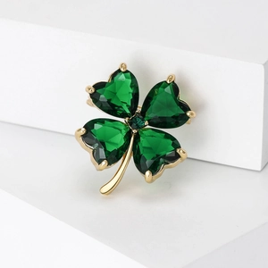 Detailed macro view of high-end golden four-leaf clover brooch with green heart crystals