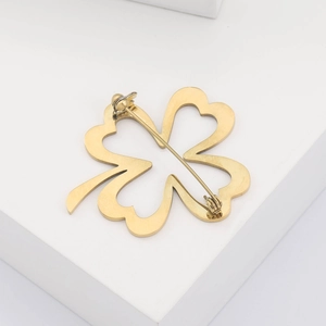 Detail view of the golden four-leaf clover brooch back with a secure silver pin mechanism