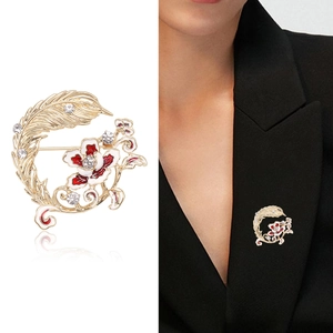 Broche élégante en plume dorée et fleur émaillée avec strass sur costume et fond blanc neutre