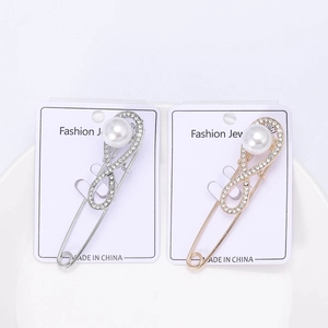 Detailed close-up of pearl and rhinestone infinity brooches in gold and silver plating