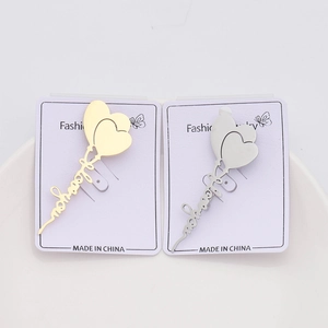 Detail view of heart balloon brooches in gold and silver finish on white jewelry card