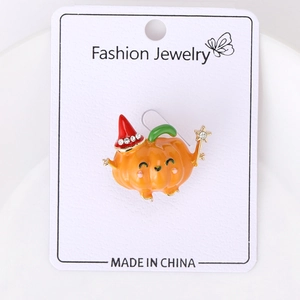 Macro view of orange enamel pumpkin brooch with red pointed hat and white rhinestones
