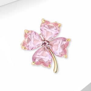 Detailed close-up of a pink heart-shaped crystal clover brooch with a gold plating finish
