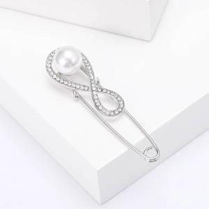 Close-up of silver infinity brooch with sparkling rhinestones and a white pearl accent