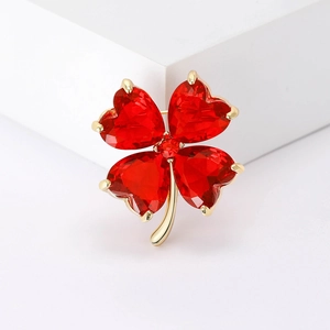 Macro view of gold clover brooch featuring four red heart-shaped crystal gemstones