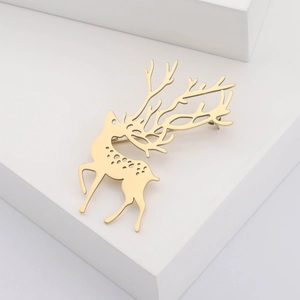 Minimalistische goldene Elch-Brosche aus Titanstahl mit hohlpunkten auf weißem Sockel