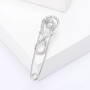 Close-up of a silver infinity safety pin brooch with a hammered metal texture finish
