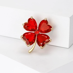 Detail of red heart-shaped crystals on a golden four-leaf clover brooch jewelry piece