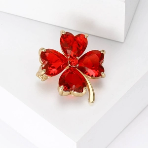 Close-up of four-leaf clover brooch with red heart crystals and gold-plated finish