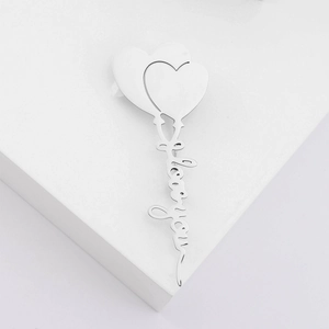 Polished heart shaped stainless steel brooch with I Love You lettering on a white stand