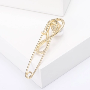 Detail view of gold safety pin brooch with infinity swirl and elegant white pearl