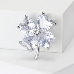 Macro detail of the silver polished four-leaf clover brooch with heart-shaped crystals