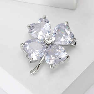 Detailed close-up of heart-shaped crystal clover brooch with silver prong setting