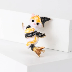 Detailed view of enamel cat wizard brooch with hat and broom on white background