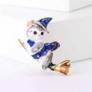 Close-up of a white enamel cat wizard brooch riding a golden broom with glossy finish