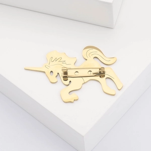 Detail view of the golden unicorn brooch featuring a secure pin clasp on a metal backing