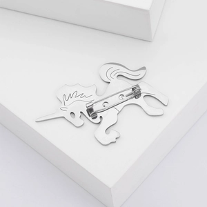 Detailed close-up of a silver unicorn brooch with a secure safety pin on its back