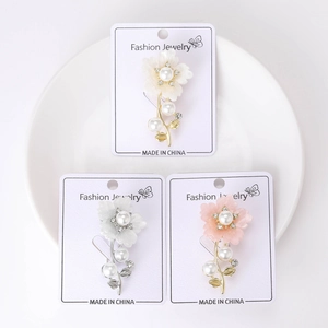 Vue détaillée de trois broches florales avec perles et strass sur support blanc