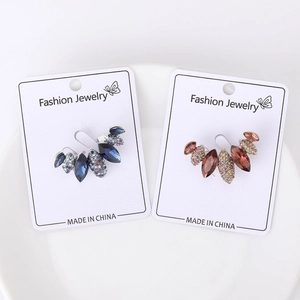 Macro detail of elegant marquise crystal ear cuffs in blue and amber tones on white base
