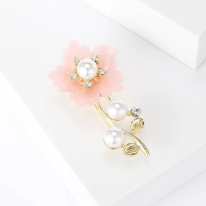 Détail de la broche fleur avec pétales roses, perles blanches et cristaux brillants
