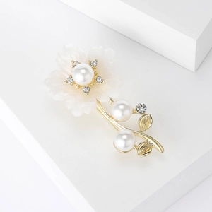 Gros plan de la broche fleur blanche avec perle centrale et détails en strass