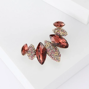 Detailed macro view of an elegant brooch featuring deep maroon crystals on a white pedestal