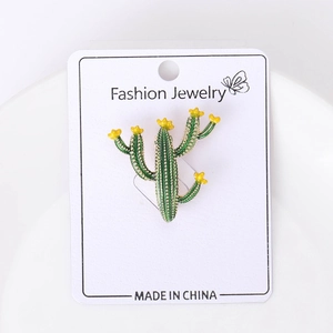 Gros plan d'une broche cactus verte avec fleurs jaunes sur carte de présentation bijoux
