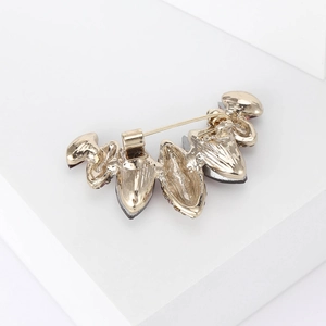 Detail of the golden brooch back showing the safety pin clasp and dark crystal settings