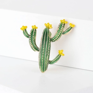 Détail d'une broche cactus en émail vert avec fleurs jaunes et finitions en alliage doré