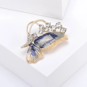 Detail of butterfly brooch with blue enamel wings and sparkling crystals on gold metal