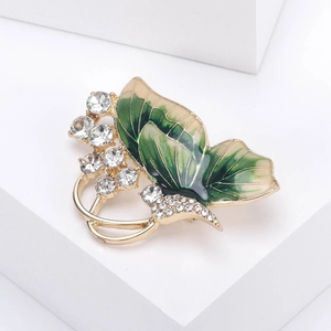 Detailed macro view of butterfly brooch with green enamel wings and white rhinestones