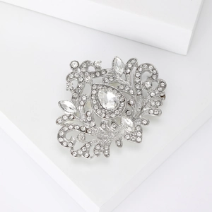 Gros plan d'une broche vintage avec strass en forme de poire et détails argentés fins