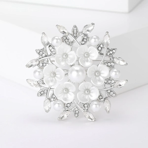Eleganter Blumenperlenbrosche mit Silberblättern und Straßsteinen auf weißem Untergrund