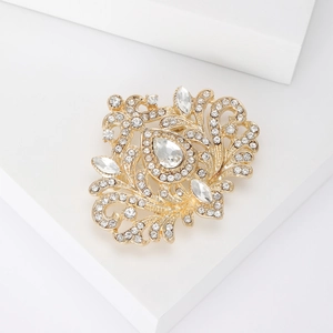 Détail macro d'une broche baroque dorée avec des strass étincelants et une pierre goutte