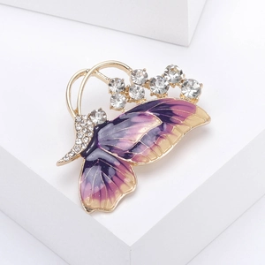 Detailed macro of a gold butterfly brooch with purple enamel and sparkling rhinestones