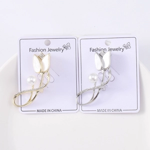 Detailed view of gold and silver tulip brooches with pearls and rhinestones on card