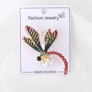 Détail d'une broche libellule colorée avec strass multicolores et une perle blanche