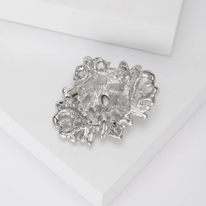 Détails de l'arrière d'une broche argentée avec épingle de sûreté et motifs évidés