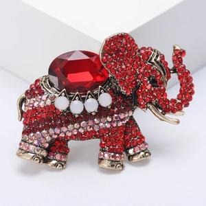 Vintage gold elephant brooch with red rhinestones and oval gemstone on white background