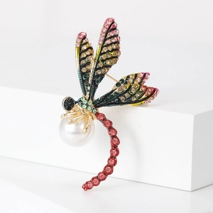 Détail d'une broche libellule de luxe avec strass colorés et accent de perle blanche