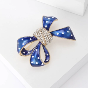 Détail de la broche nœud en émail bleu à pois blancs et centre serti de strass
